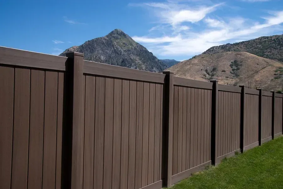 Brown vinyl privacy fence with the Idaho foothills rising behind it