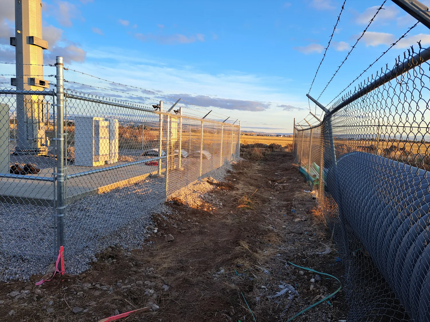 Chain link security fence topped with three strand barbed wire arms