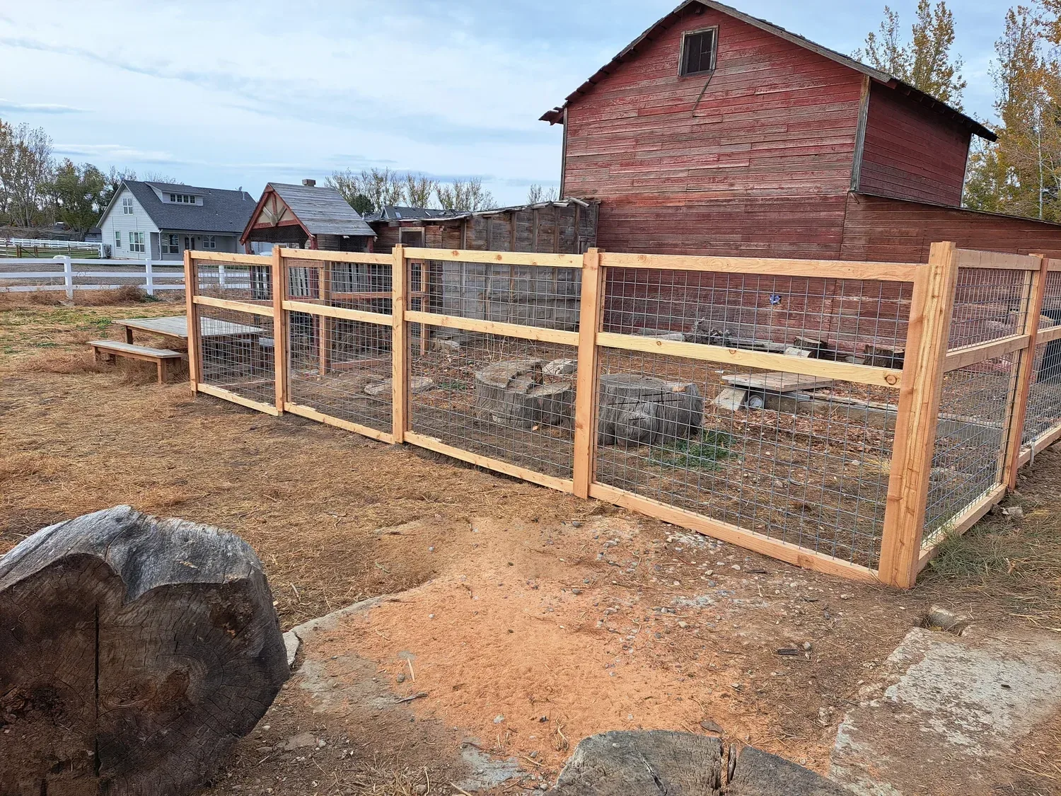 Custom cedar and wire chicken run built beside a red barn in Kuna, Idaho