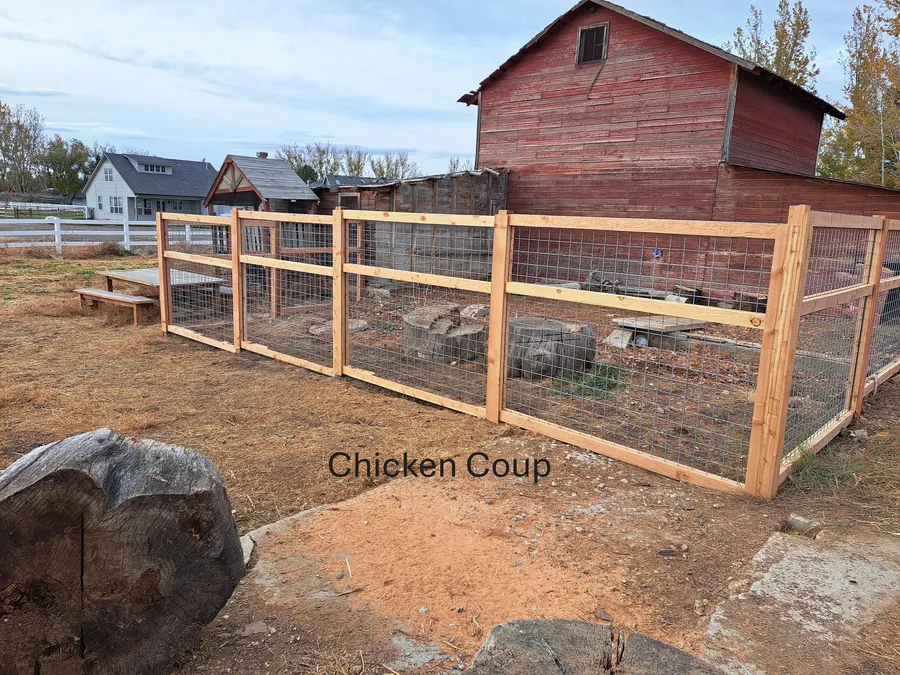 Custom cedar and wire chicken run built beside a red barn in Kuna, Idaho