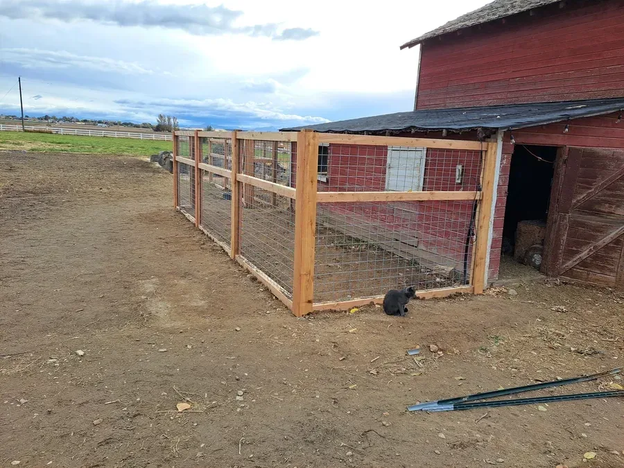 Custom livestock enclosure fence beside an Idaho barn