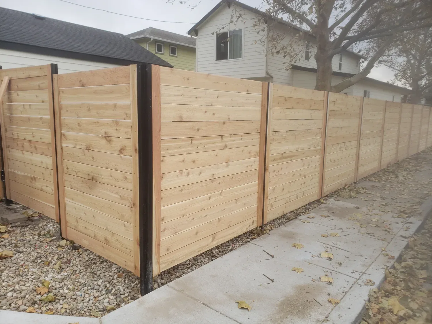 Horizontal cedar fence with black steel posts between two homes in Meridian, Idaho