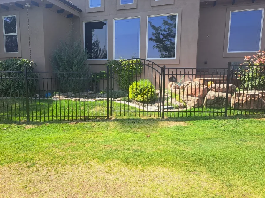 Staggered vista wrought iron fence with a curved top gate at a stucco home in Meridian, Idaho