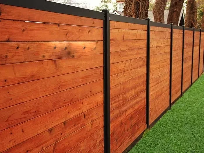 Freshly stained horizontal cedar picture frame fence with black posts