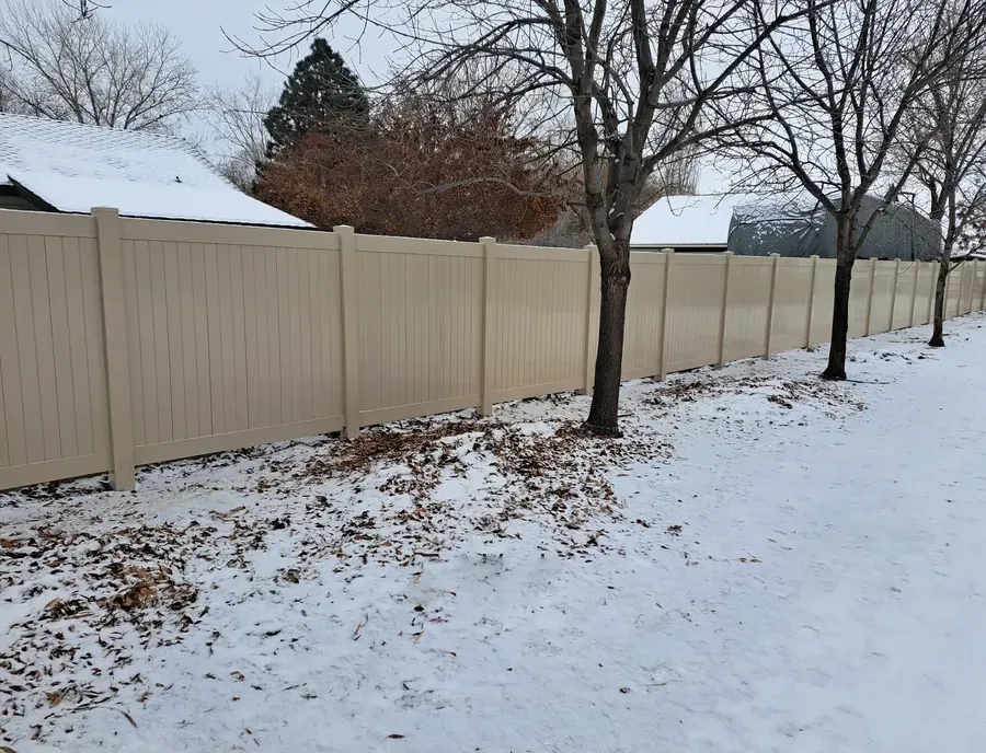 Tan vinyl privacy fence standing through fresh snow in the Treasure Valley