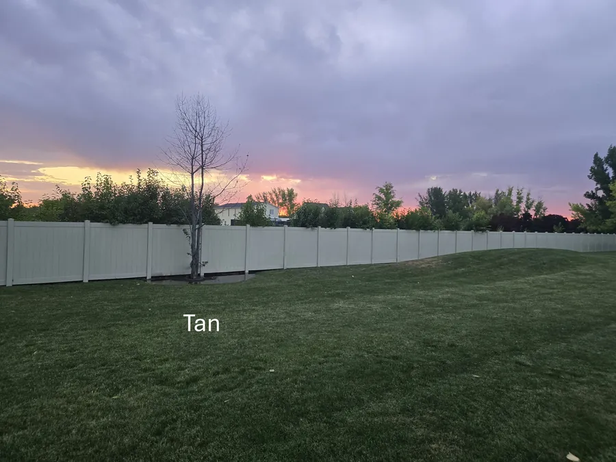 Tan vinyl privacy fence around a Kuna, Idaho backyard at sunset