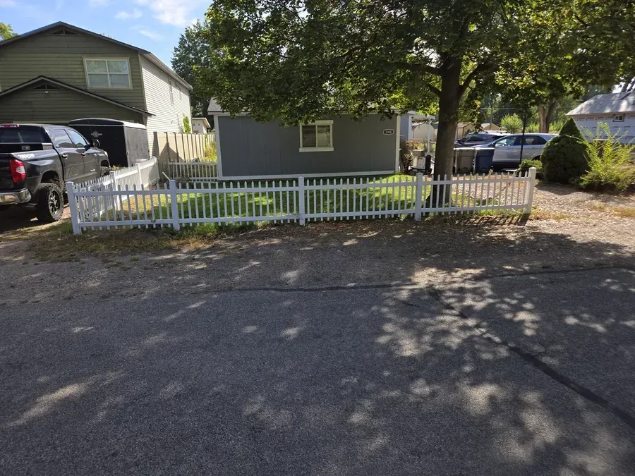 White vinyl picket fence enclosing a front yard in Caldwell, Idaho