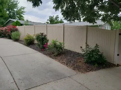 White vinyl privacy fence behind flowering landscaping at a Boise home
